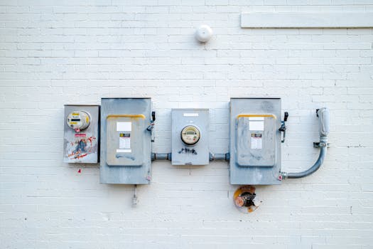 Electrical boxes and power meters mounted on a white brick wall.