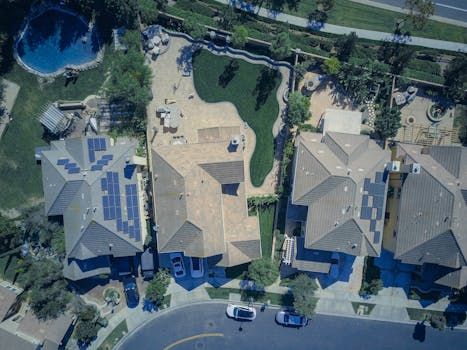 Aerial view of suburban houses featuring solar panels and green lawns, symbolizing eco-friendly living.